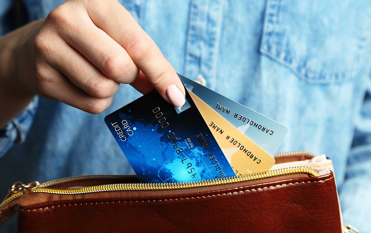 3 credit cards are being pulled out of a wallet